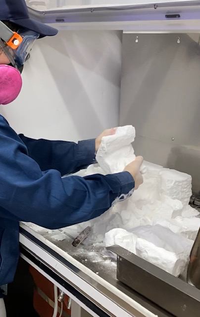 An engineer retrieving a printed part from the powder bed